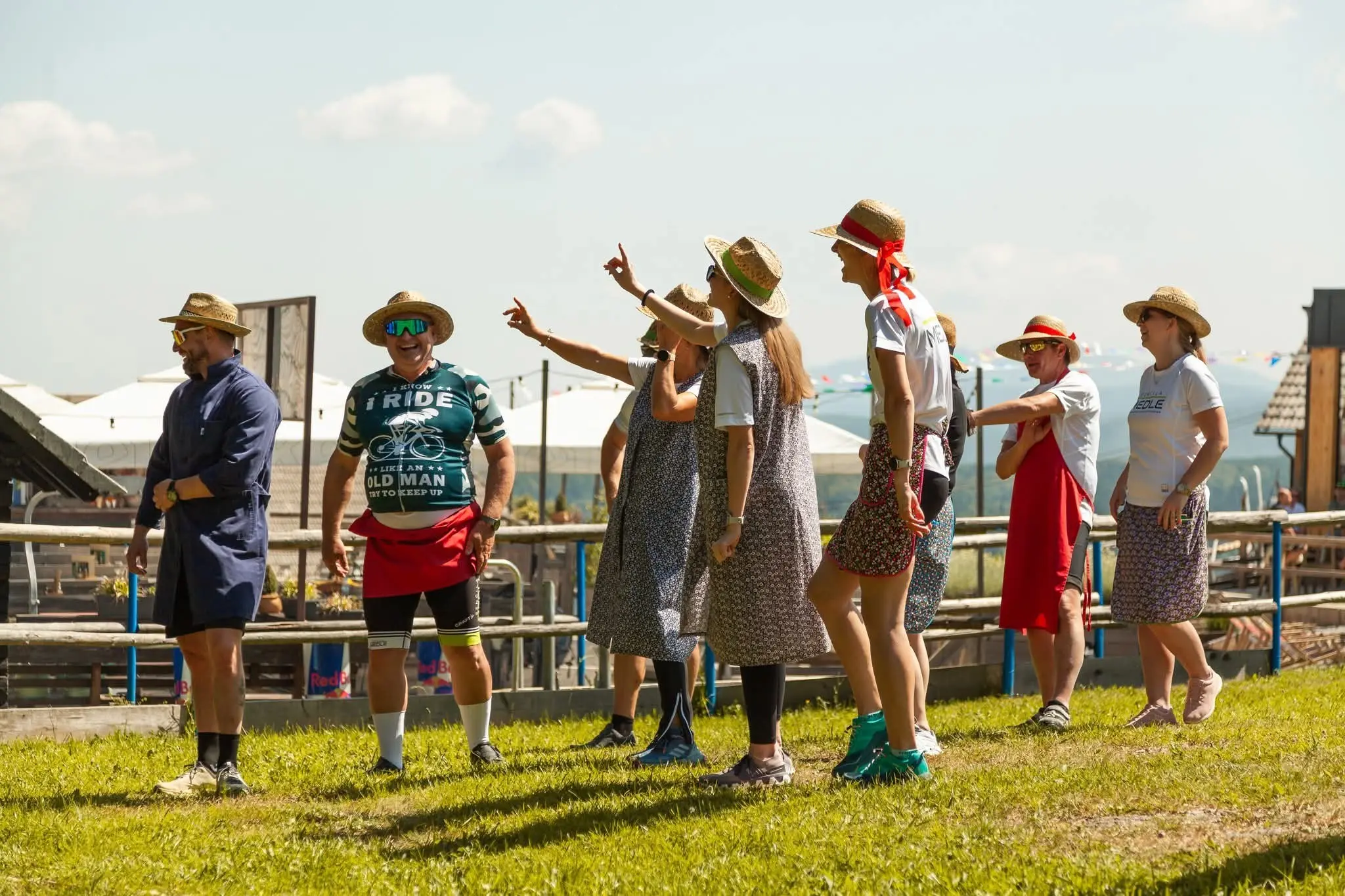 Skupina ljudi stoji na travniku, nekateri v slamnikih, drugi v športnih oblačilih.