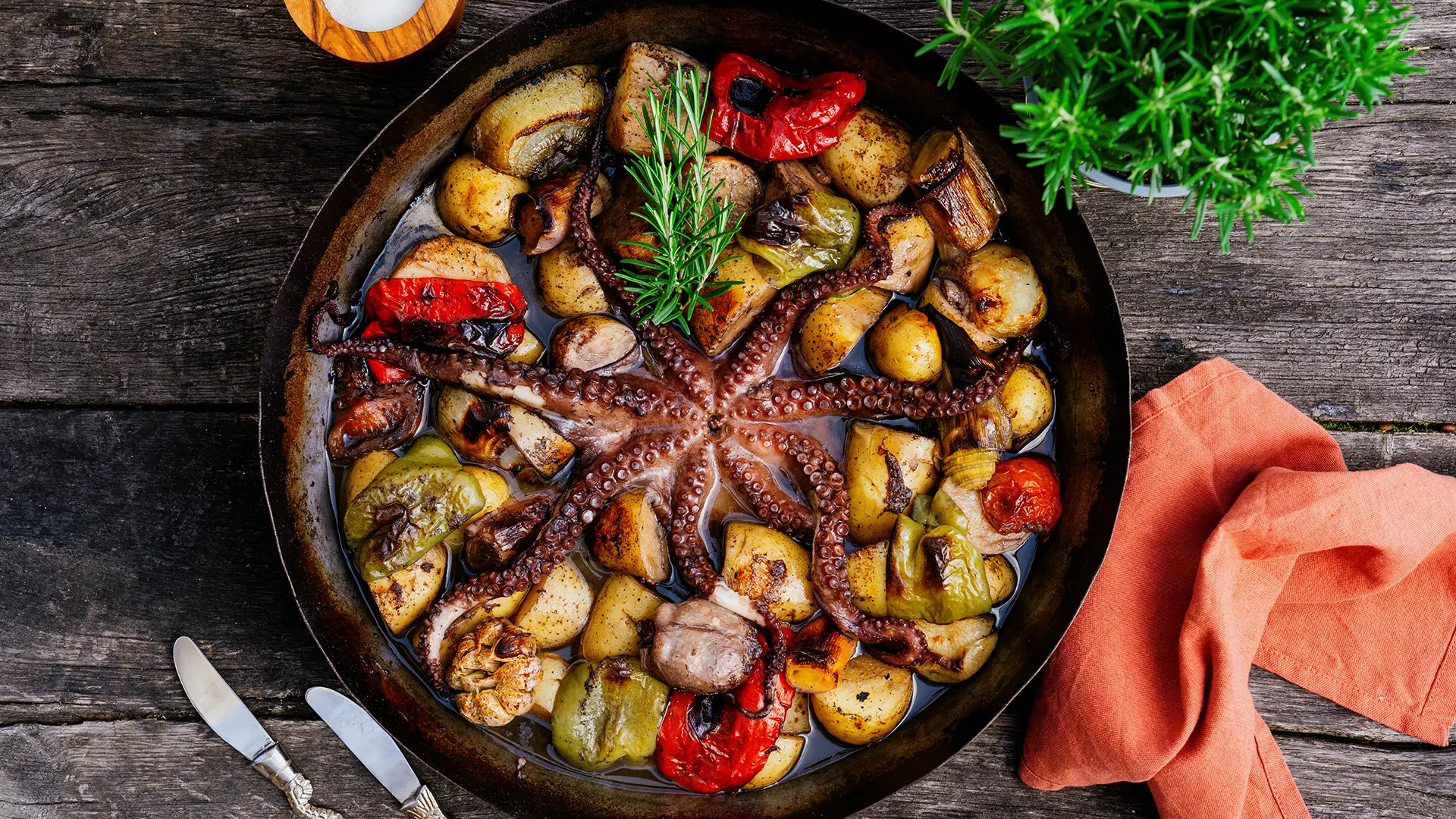 Pogled od zgoraj na hobotnico s krompirjem in zelenjavo v ponvi